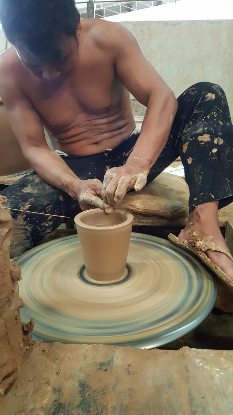 Thai artisan hand-forming a terracotta pot on a spinning pottery wheel