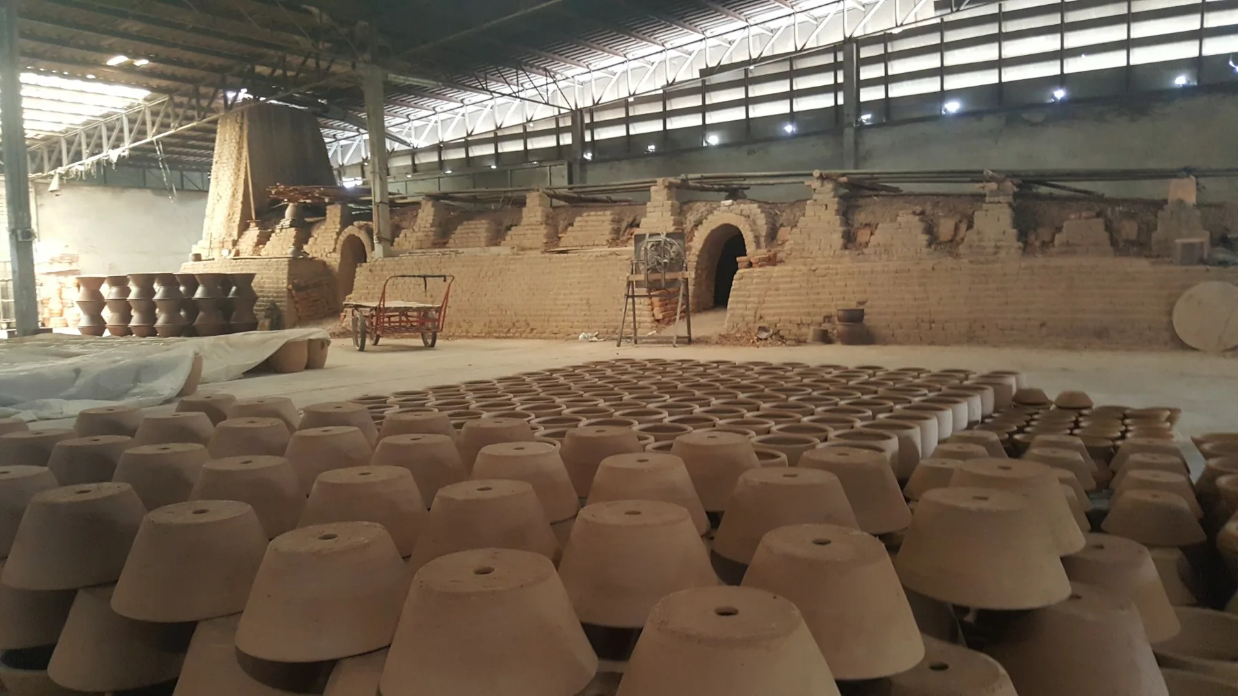 Thai pottery workshop with rows of pots and traditional kilns